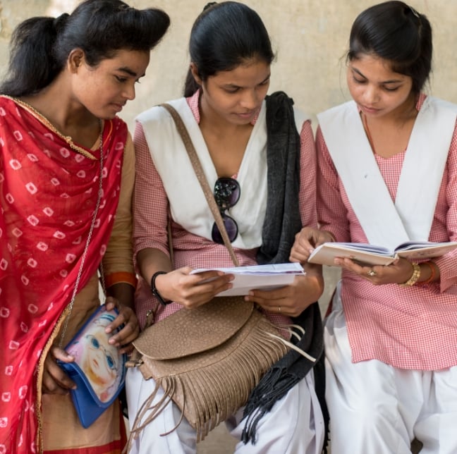 Three young girls sitting together and smiling.