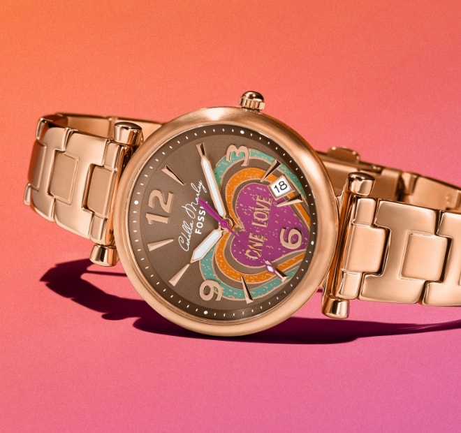 Gold-tone Cedella Marley x Fossil watch on a pink background.