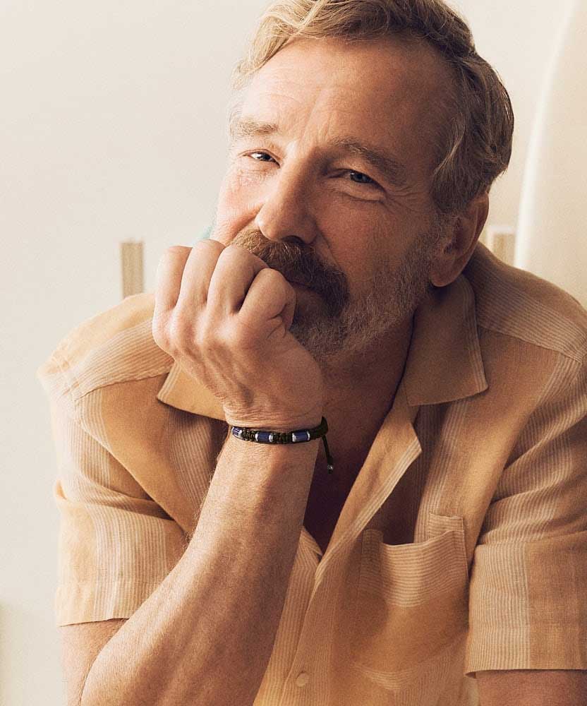 Man with his hand on his chin wearing a Fossil bracelet.