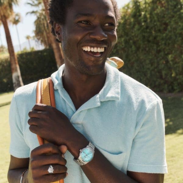 A man in a light blue shirt wearing a Fossil silver-tone watch with light blue dial.