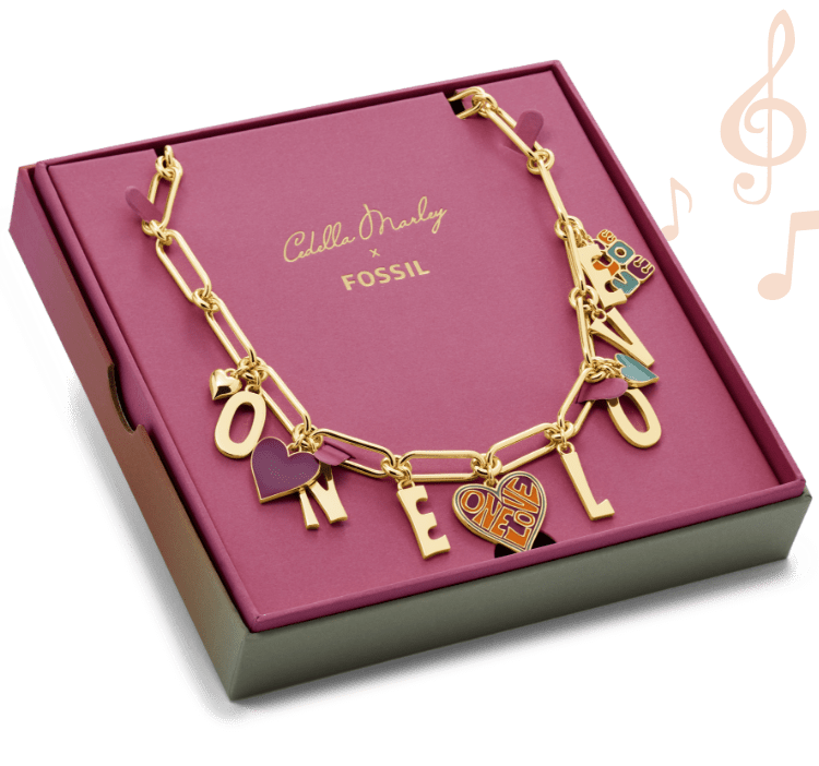 Die goldfarbene Cedella Marley x Fossil Halskette mit „One Love“-Charmanhängern in einer rosafarbenen Box. Grafiken von Musiknoten.