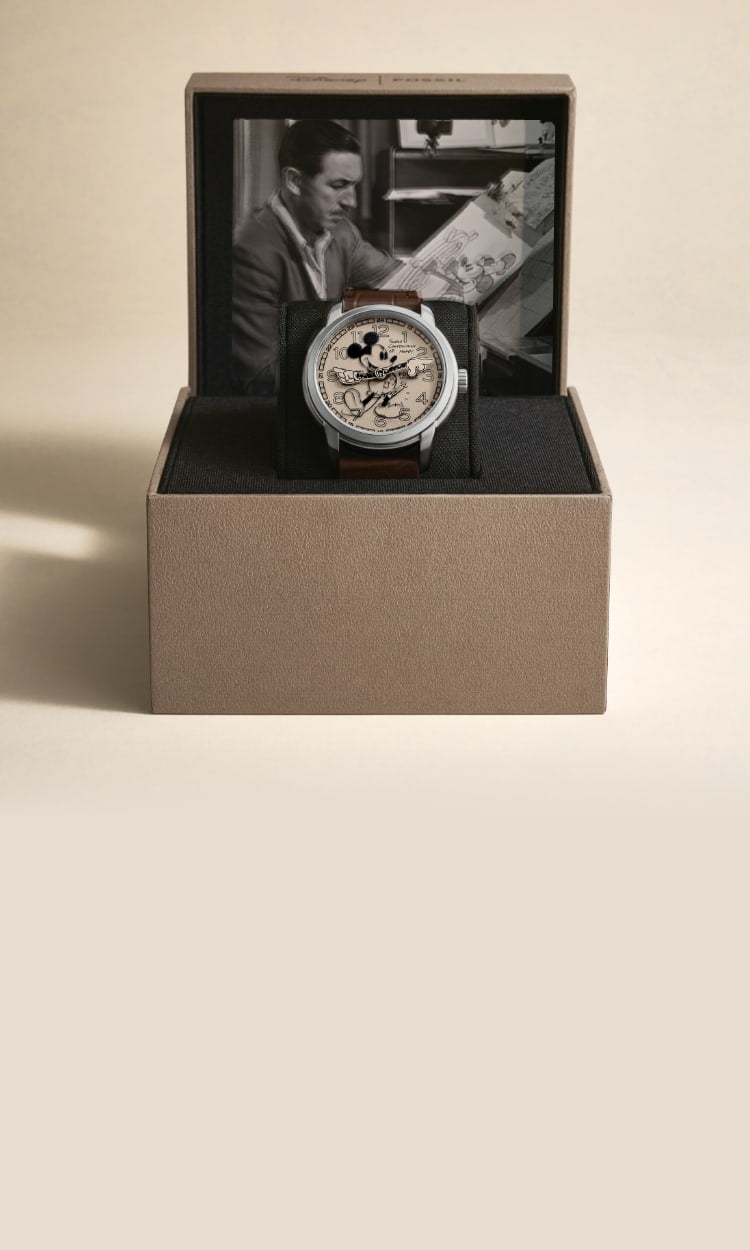 The collectible packaging features a light brown box with a black-and-white photograph of Walt Disney drawing in his animation studio. The box is open to display the Classic Disney Mickey Mouse Watch.