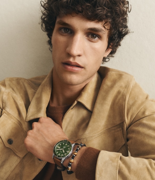 Uomo che indossa un orologio Fossil con quadrante verde. 