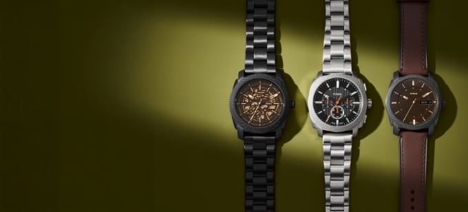 A close-up view of three Fossil Machine watches: automatic, chronograph and three-hand on an olive green background.