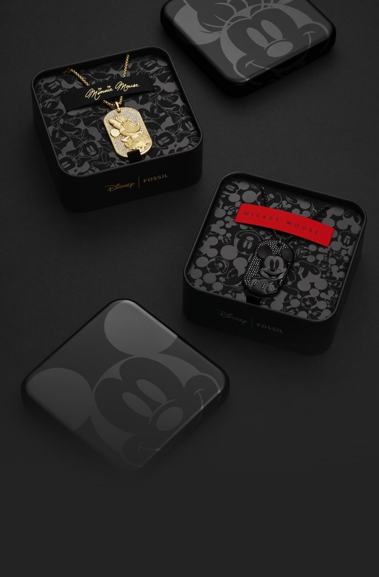 Deux boîtes noires à collectionner sont ouvertes pour présenter un collier Minnie doré et un collier Mickey entièrement noir. Le dessus du couvercle de la boîte et l’intérieur sont décorés de dessins noirs inspirés de la silhouette de Mickey.