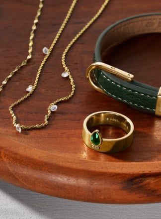 Bijoux dorés ornés de cristaux verts et bracelet en cuir dans les mêmes tons 