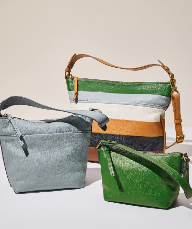 Drei Damenumhängetaschen mit einer lässigen Silhouette. Die kleine Tasche ist grün, die mittelgroße Tasche ist hellblau und die große Tasche hat blaue, grüne und hellbraune Streifen.