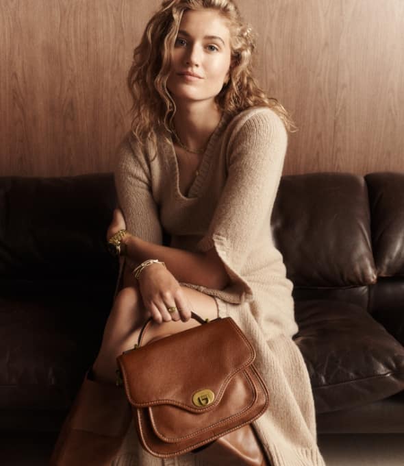 A woman holding a suede Fossil Heritage handbag.