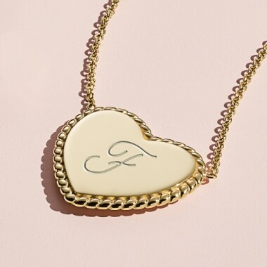 A woman's gold-tone engravable heart pendant.