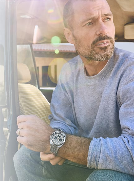 A lifestyle image of a man wearing the Fossil Everett Chronograph watch looks off into the distance.