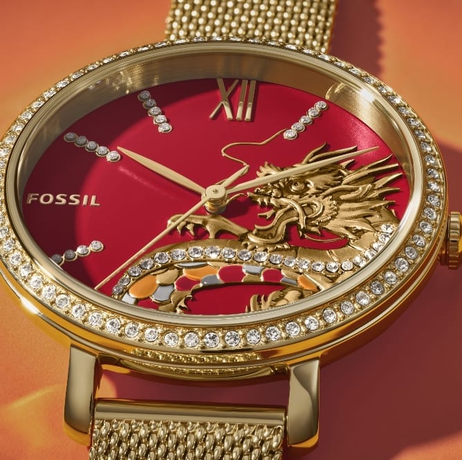 Die goldfarbene Uhr Jacqueline mit Drachendetail und Glassteinen auf dem roten Zifferblatt.
