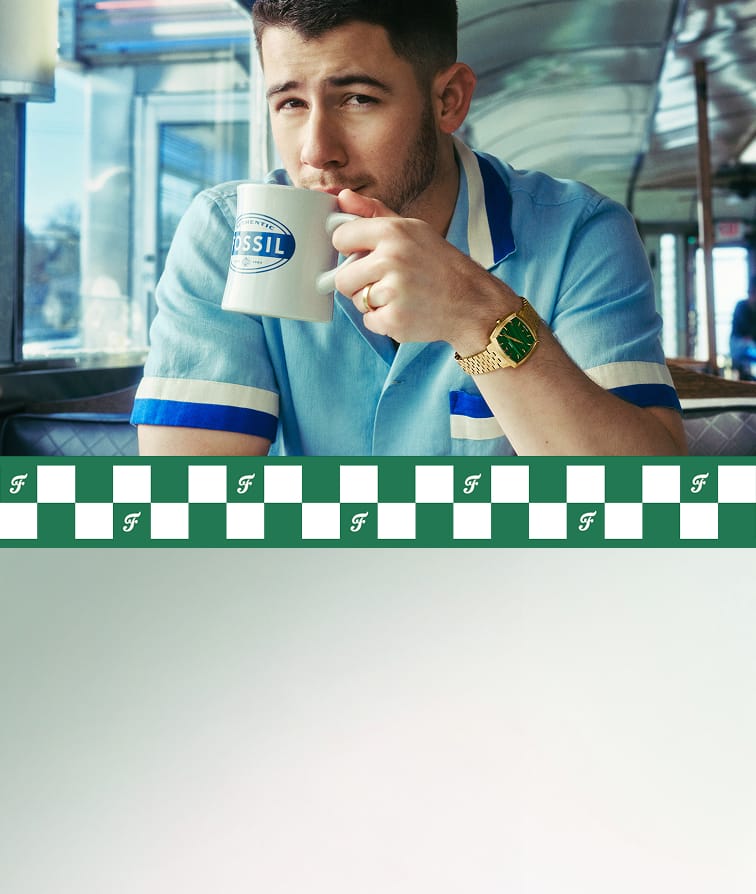 Nick Jonas sitting in a diner, drinking from a Fossil coffee mug and wearing the gold-toned Machine Luxe watch with a green malachite dial. Plus, a close-up of that same watch.