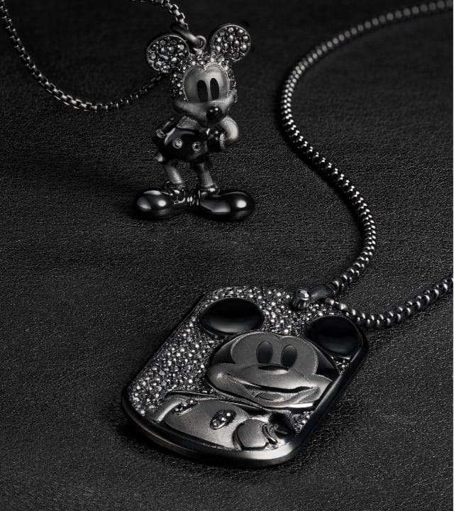 Ein GIF mit komplett schwarzem Schmuck mit Disneys Micky Maus. Zwei Halsketten mit schwarzen Glassteinen. Das zweite GIF zeigt einen Anhänger mit Disneys Minnie Maus aus goldfarbenem Edelstahl mit funkelnden Glassteinen, die ihre Silhouette im Profil zum Funkeln bringen. 