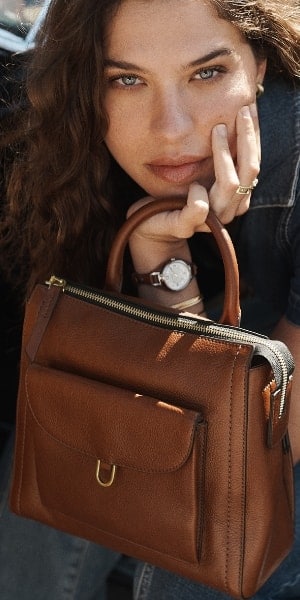 Une femme tenant le sac à dos Parker Mini en cuir brun. Une image de quatre sacs à dos Parker Mini en noir, bleu poudre, brun foncé et brun pâle. 