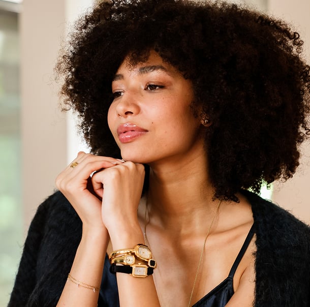An elegantly dressed woman wearing a triple stack of festive, party-style watches.