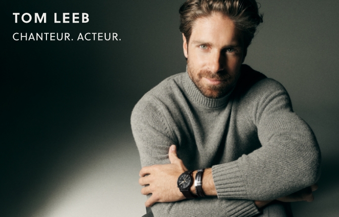 Tom Leeb pose avec une montre Fossil Minimalist Chrono noire et un bracelet Fossil en cuir noir