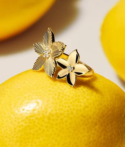 Gold-tone earrings resting on a lemon.