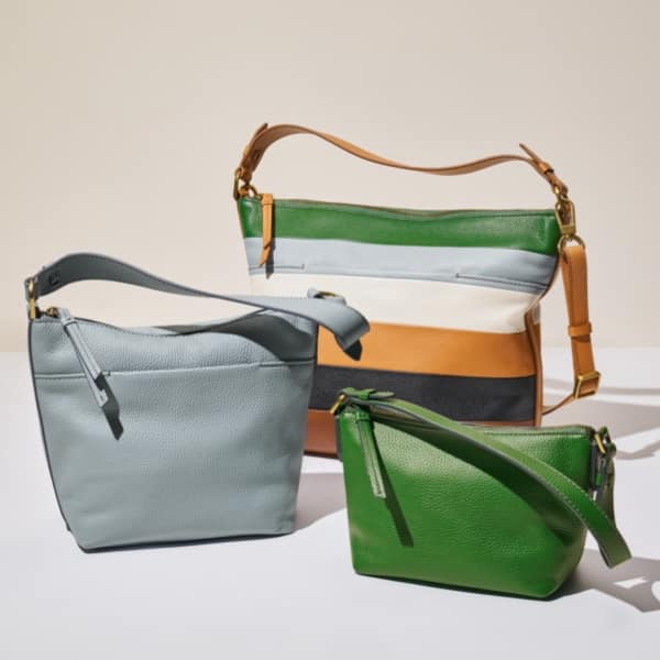Three women’s shoulder bags with a relaxed silhouette. The small bag is green, the medium bag is light blue and the large bag features blue, green and tan stripes.