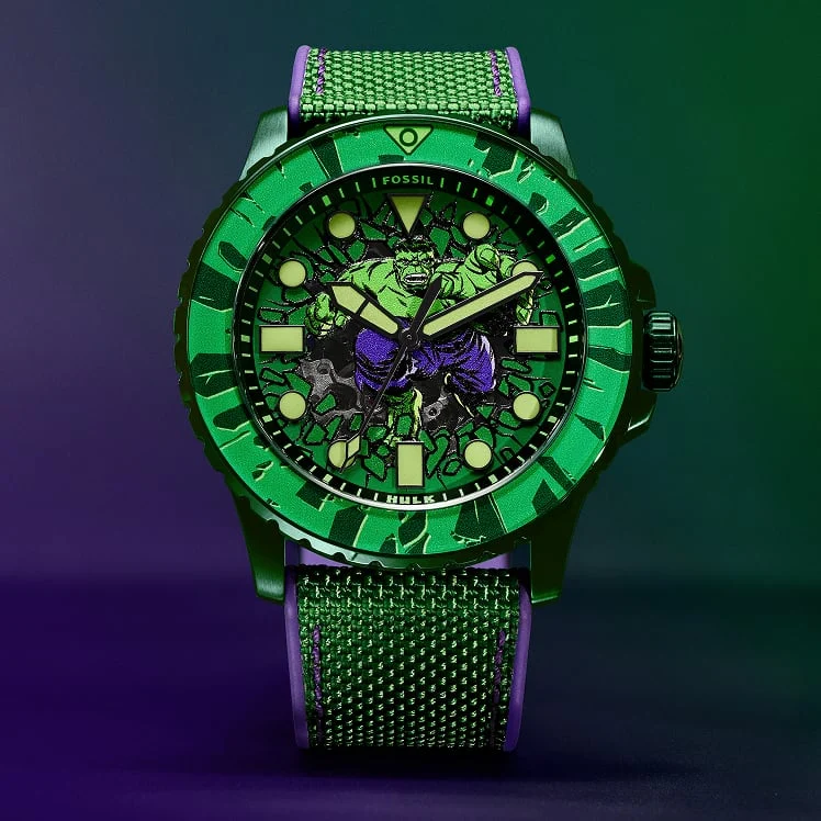 A full view of the green and purple Fossil Hulk watch that shows the oversized case, graphic comic-style dial and nylon and silicone strap.
