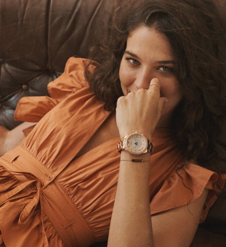 A woman smiling wearing a Gen 6 Hybrid smartwatch.