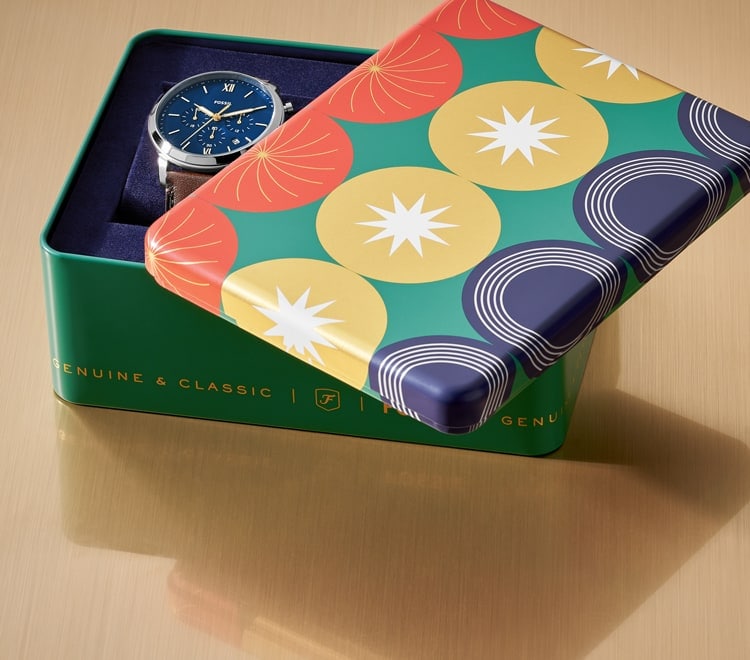 Gif of a brightly coloured Fossil gift set tin opening to reveal a men’s brown leather watch and brown leather bracelet. 