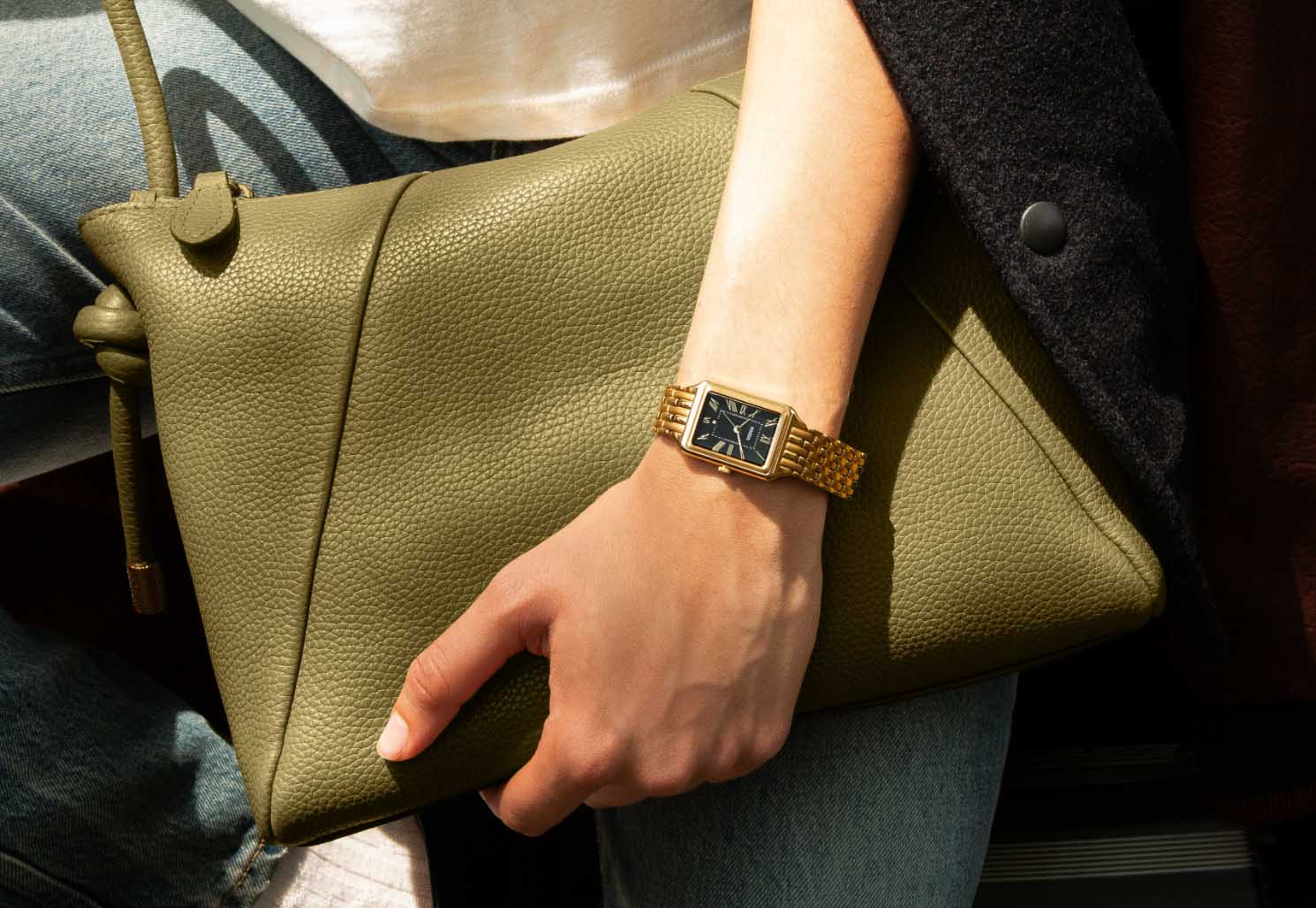 Two women sitting with a man while wearing Fossil watches, jewelry and carrying a black leather Jessie Bucket bag.