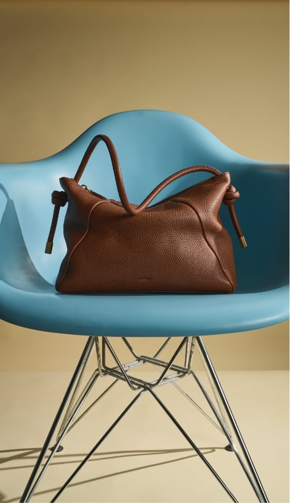 Brown leather Willa bag in a blue chair.