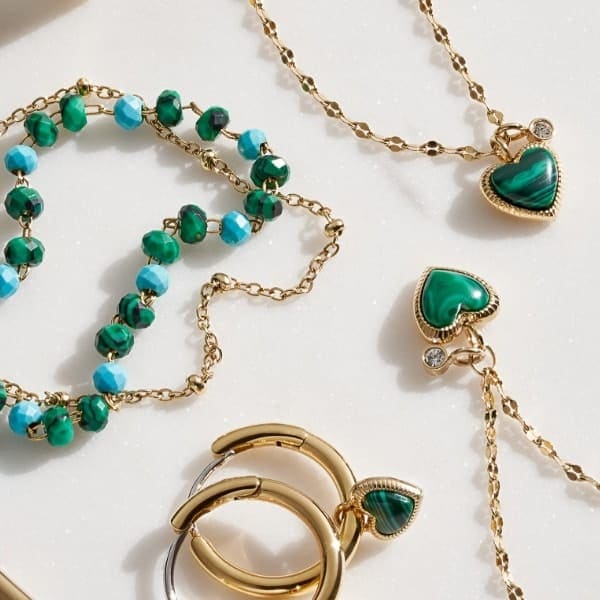 Bijoux pour femmes de ton or et malachite reconstitué, comprenant des boucles d’oreilles, des colliers et des bracelets.