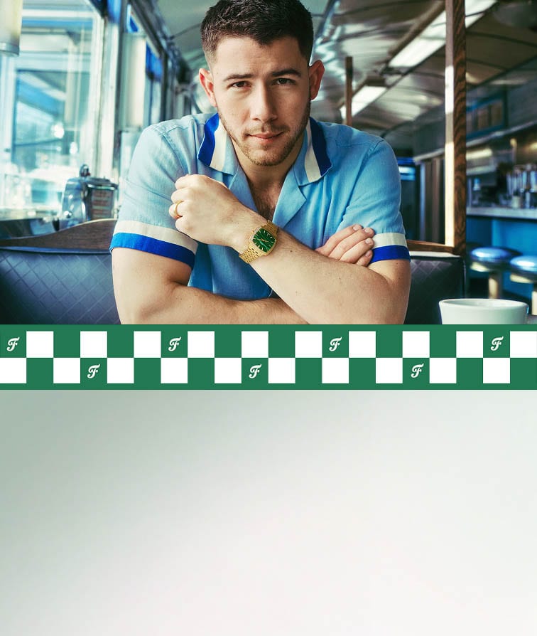 Nick Jonas sitting in a diner, drinking from a Fossil coffee mug and wearing the gold-toned Machine Luxe watch with a green malachite dial. Plus, a close-up of that same watch.