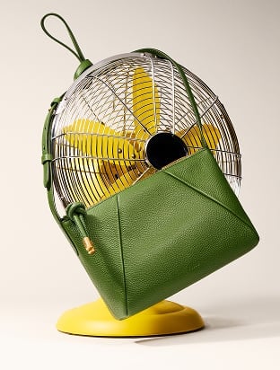 The green Willa crossbody bag playfully draped over a fan.
