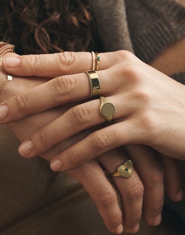 Close-up shot of a woman’s hands with Fossil rings on her fingers.