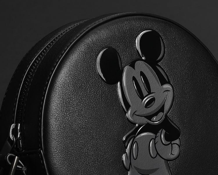 Primo piano di una borsa rotonda in pelle total black con la figura di Topolino della Disney.