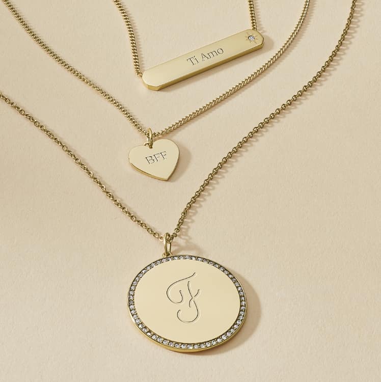 Three gold-tone necklaces engraved with initials F, K and 2023.