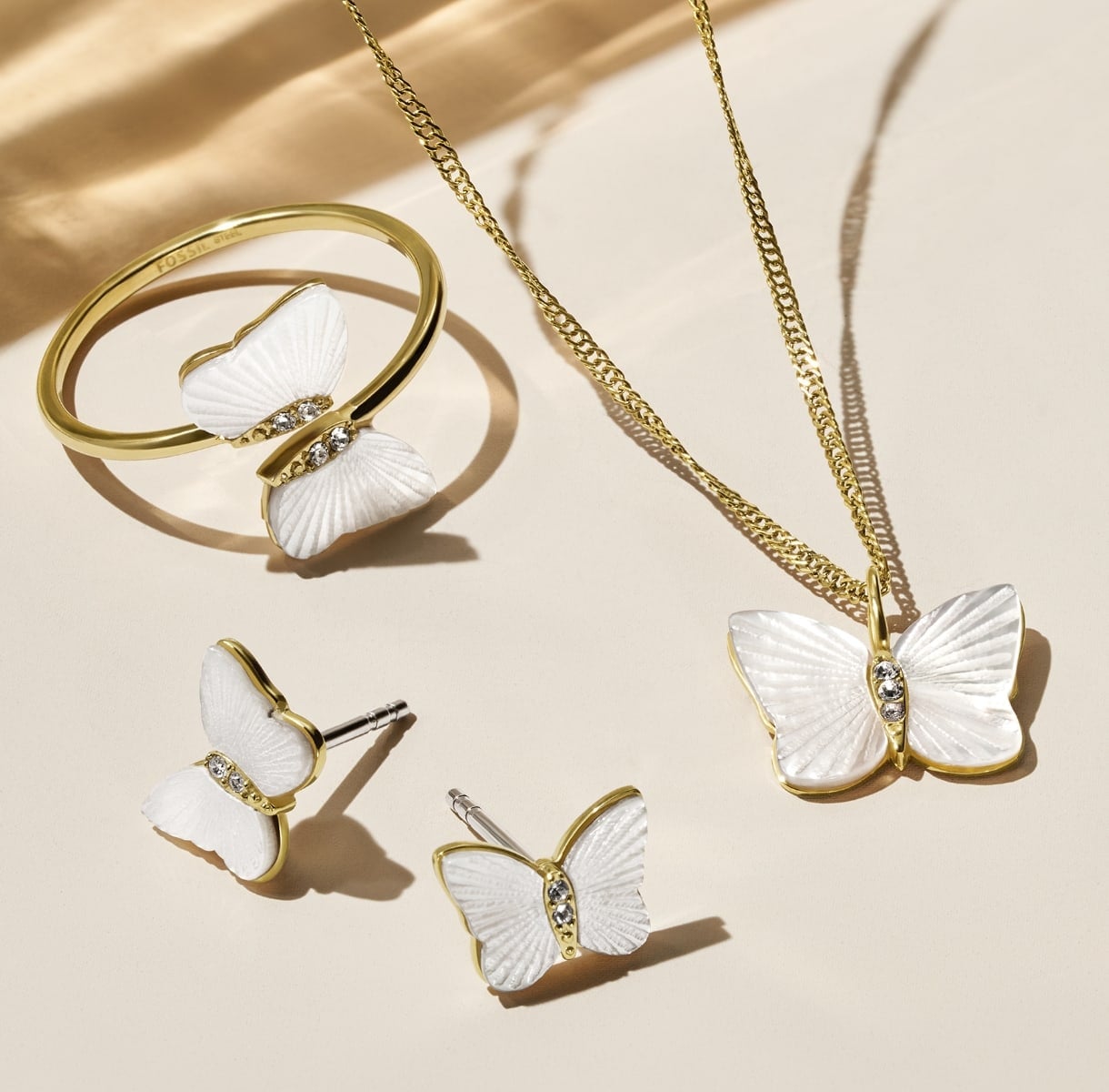A GIF of the mother-of-pearl Butterfly Collection, featuring a closeup of the necklace with crystals and a group shot of the earrings, necklace and ring.