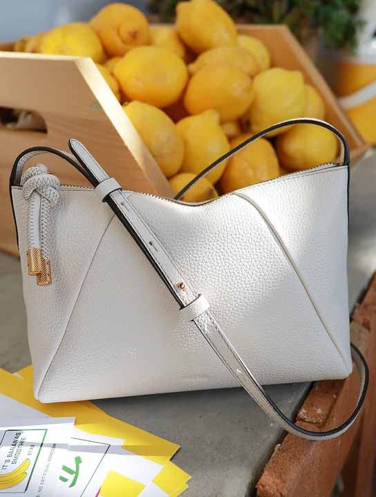 The Fossil Willa crossbody bag in white, sitting among a summery tablescape with fresh lemons.