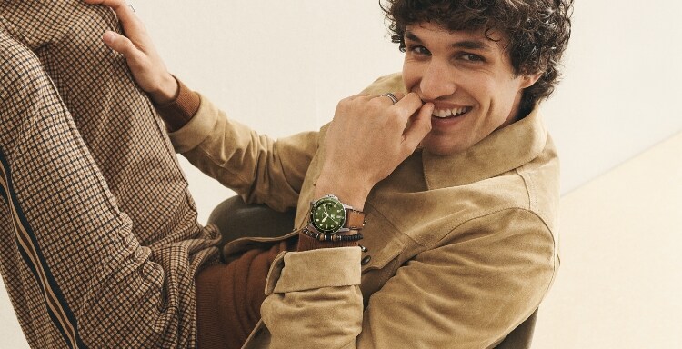 Man wearing brown leather watch with green dial. 