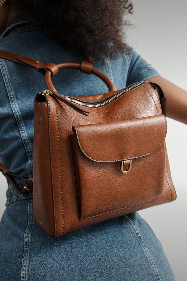 A woman wearing a brown leather Parker mini backpack.
