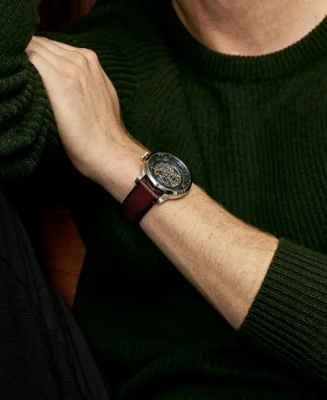 A man dressed in a blue knit sweater wearing the Townsman watch in a blue-finished dial and brown leather strap.