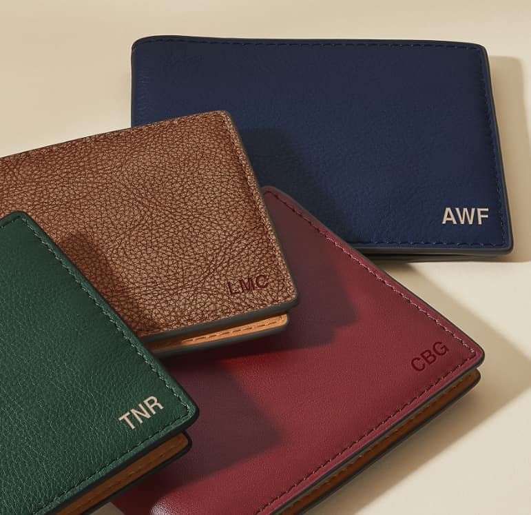 A group of various colored wallets, each embossed with initials.