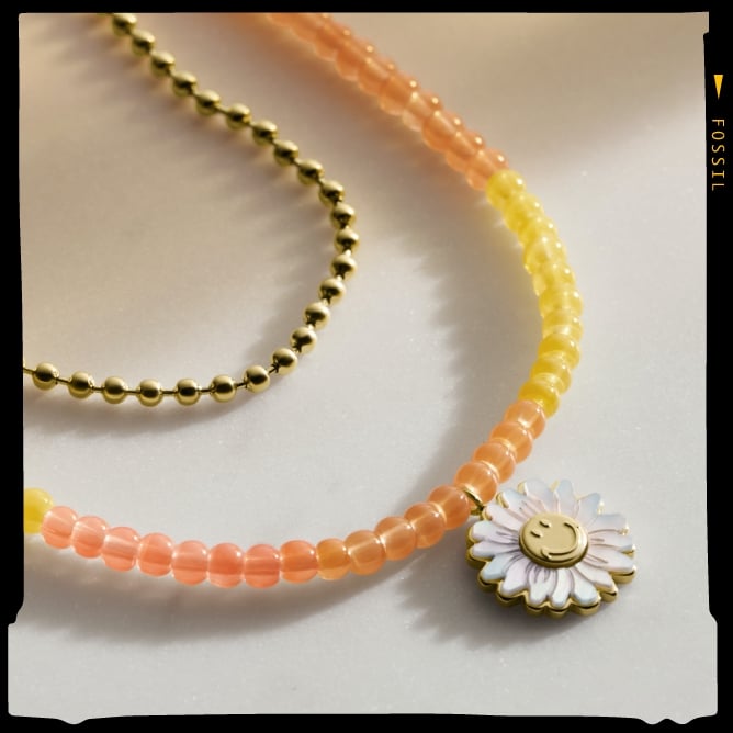 Una collana Fossil x Smiley color oro con perline. 