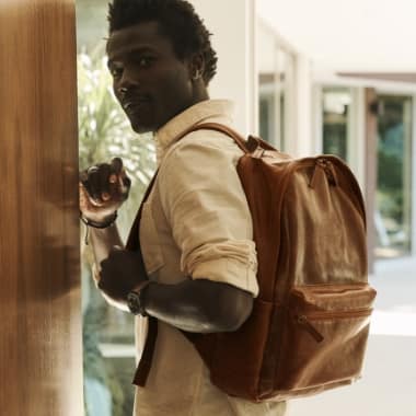 Man carrying a brown leather backpack.