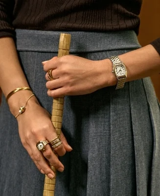 A lifestyle image of a woman wearing a gold-tone Harlow watch with a black dial.
