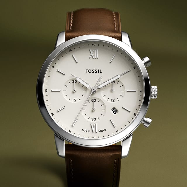 A round-faced watch featuring a chronograph movement and brown leather strap.