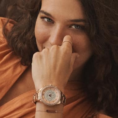Woman smiling and wearing a rose gold-tone smartwatch.