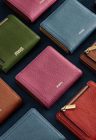 A colorful array of women's bifold wallets with a gold-tone zipper and foiled Fossil logo.