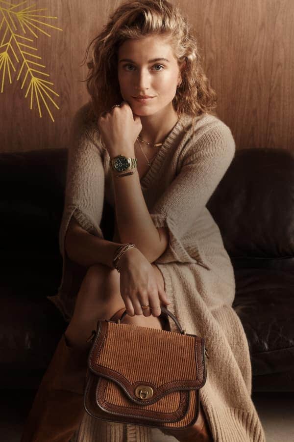 A woman smiling and holding a fossil heritage handbag.