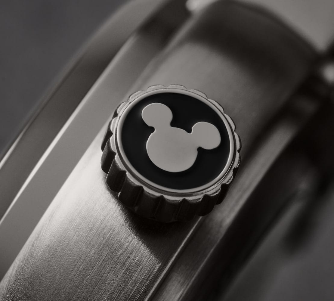 Une image détaillée de la couronne de la montre caractérisée par la silhouette de Mickey ton argent sur noir.