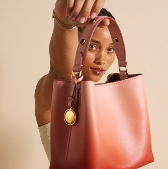 A woman holding the pink leather Jessie Bucket bag. 