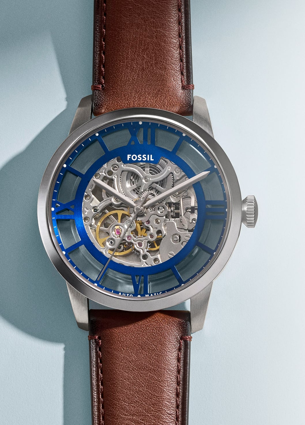An automatic watch with blue dial on a brown leather strap.