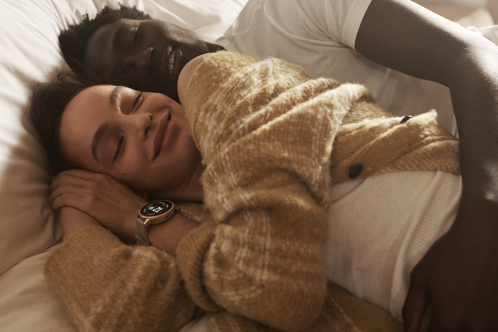 A man and a woman taking a nap with a Gen 6 smartwatch showing colorful charging rings. .